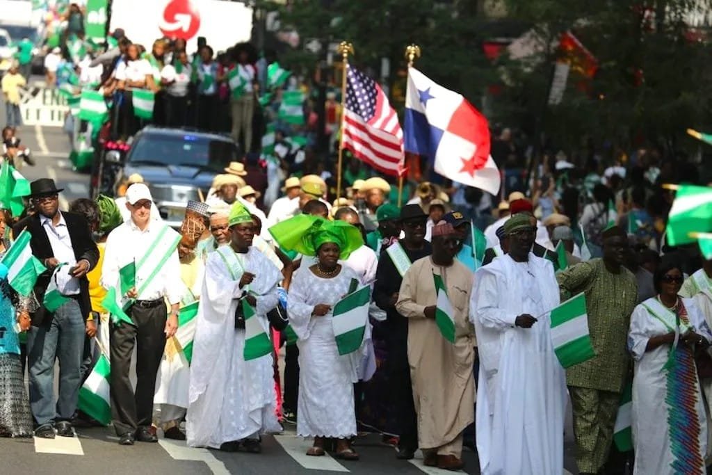 Nigerian community members marching with flags at a diaspora parade, a moment from Naijaspora Media's storytelling archive