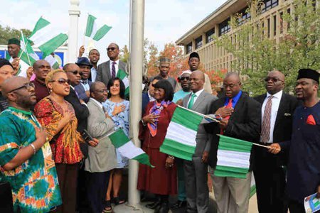 A group gathered around a flagpole for a Nigerian flag-raising ceremony