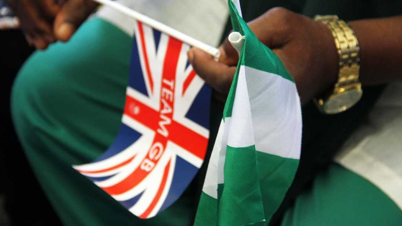 A hand holding both a Team GB flag and a Nigerian flag